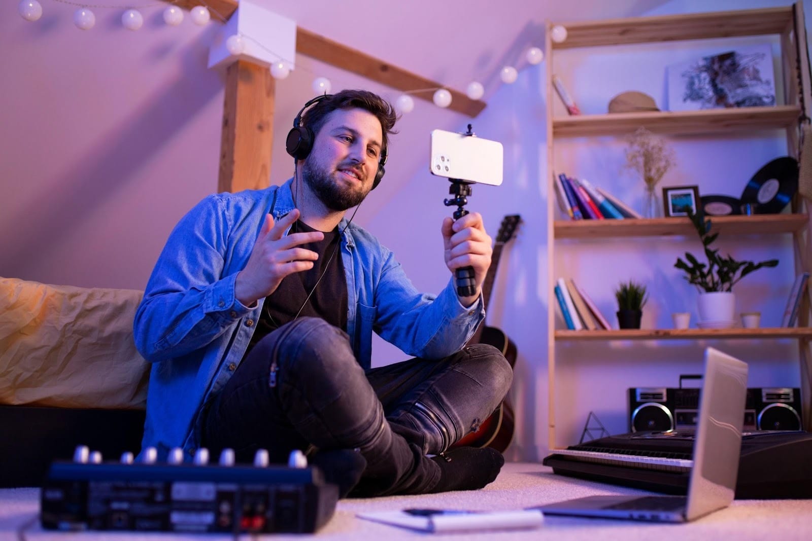 A man sitting on the floor vlogging from his smartphone while making music. Source: https://www.freepik.com/free-photo/side-view-smiley-man-making-music_33537571.htm#fromView=search&page=1&position=2&uuid=223a80c8-ea5f-4990-834f-d34f4de52269&query=tech+person+using+tiktok