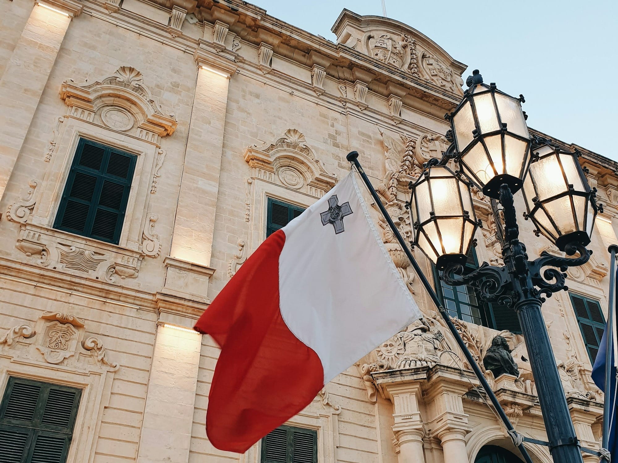 a flag hanging from a lamp post in front of a building