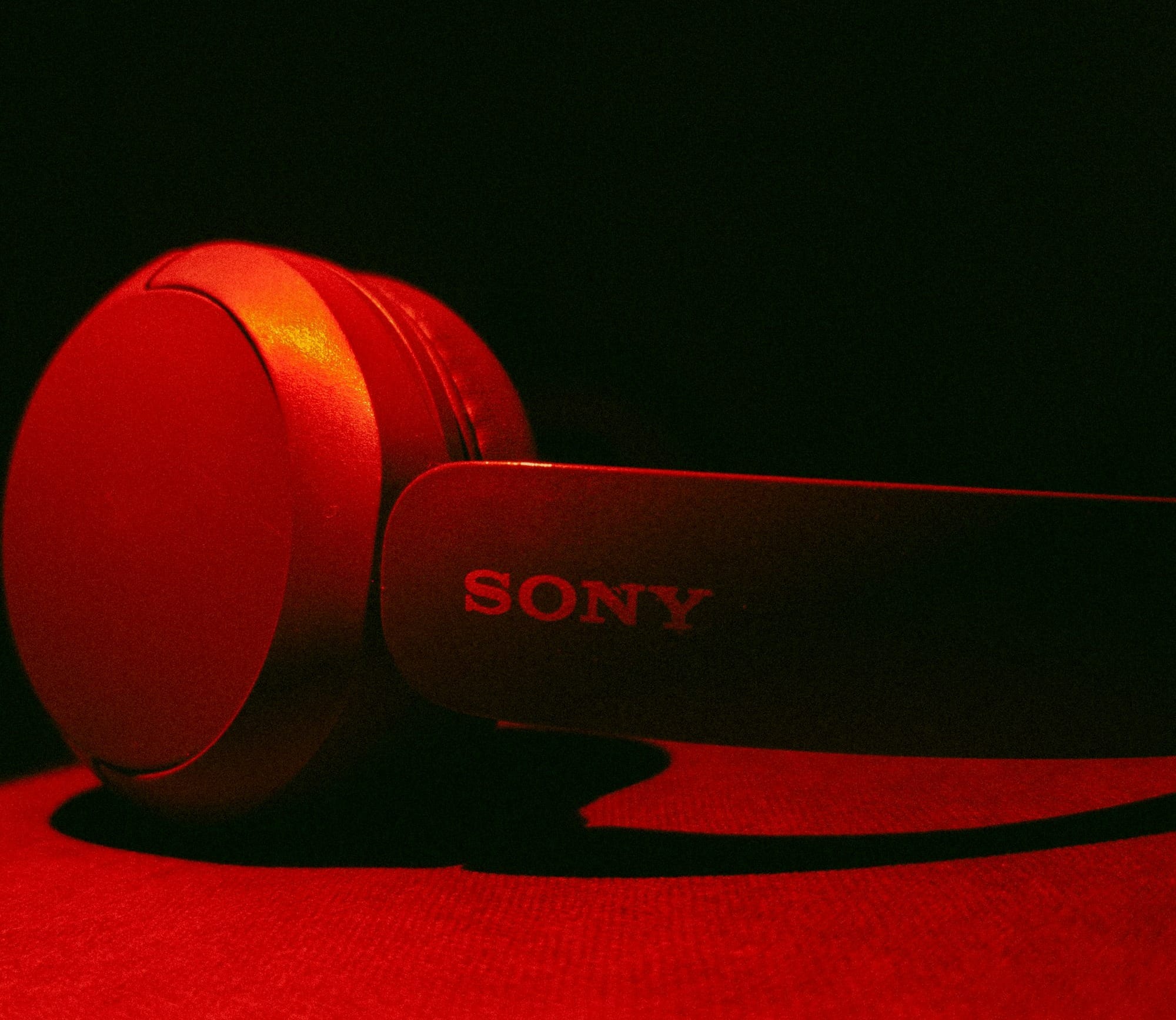 Red sony headphones resting on a dark surface.